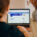 Woman using a laptop with social media open.
